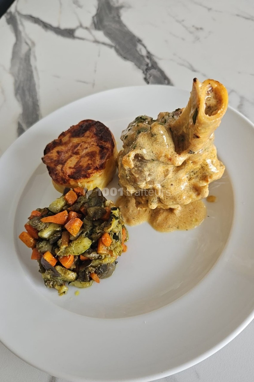 Assiette composée d'un osso buco en sauce, d'un gratin de pommes de terre et d'une poêlée de légumes colorés.