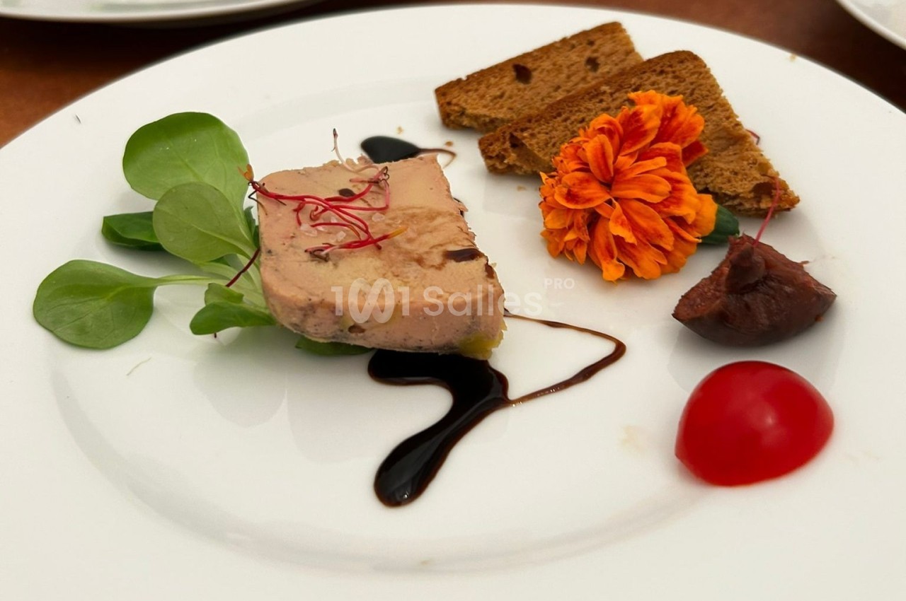 Assiette avec foie gras, pain grillé, fleur comestible, réduction balsamique, tomate cerise et verdure.