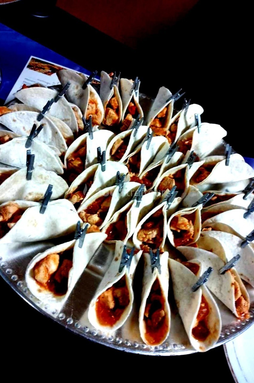 Plateau de mini-tacos garnis de poulet et maintenus par des pinces, disposés en cercle sur un plat.