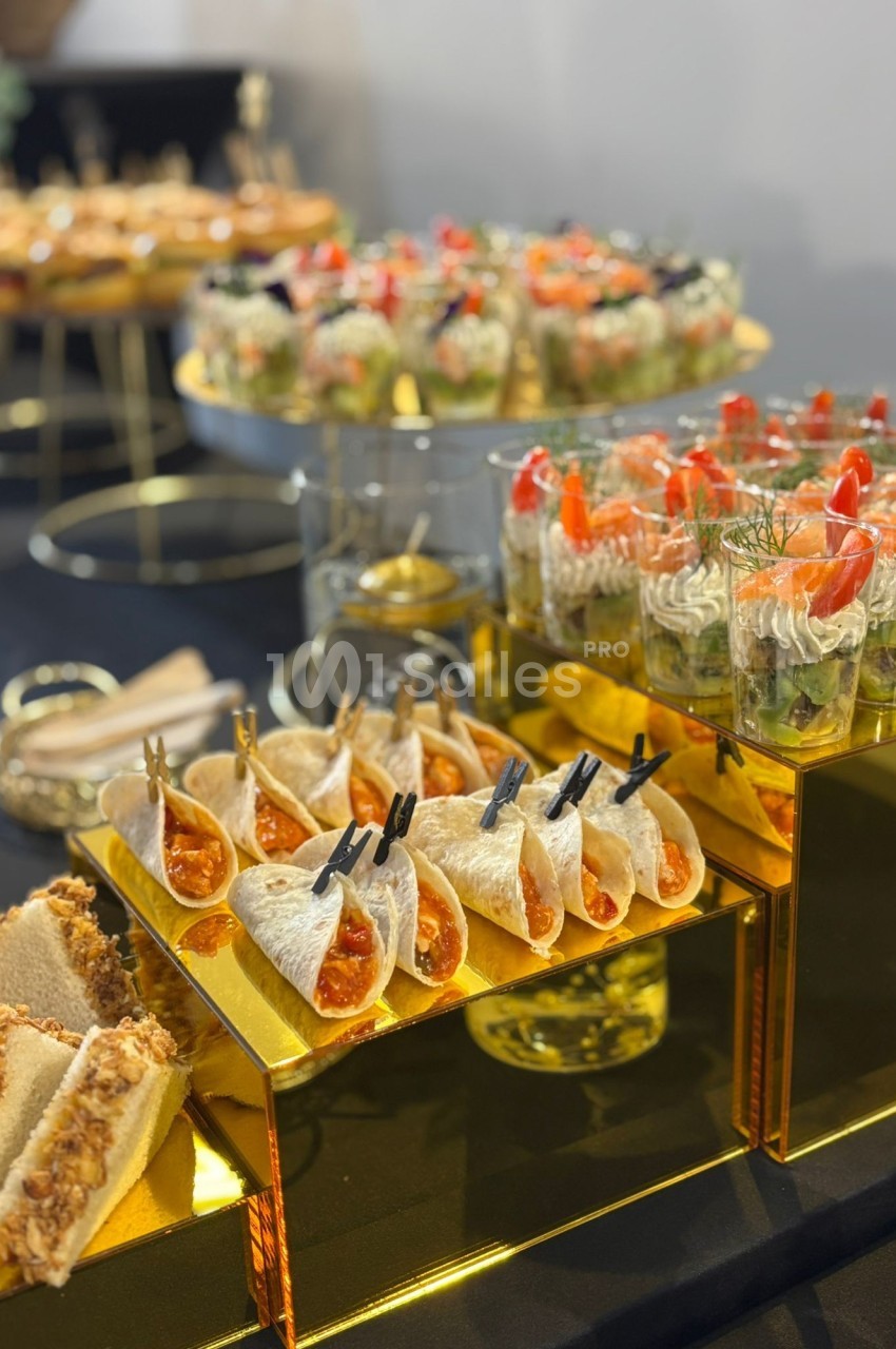 Buffet avec verrines, mini-wraps et toasts disposés sur des présentoirs dorés dans un cadre élégant.