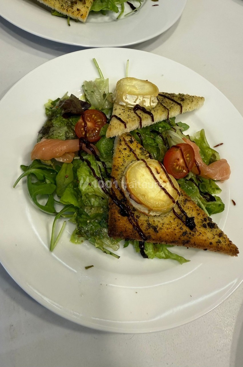 Assiette de salade verte garnie de tomates cerises, saumon fumé, toasts au fromage et filet de vinaigre balsamique.