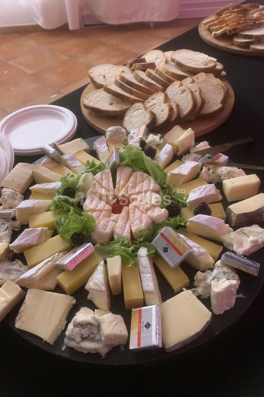 Plateau de fromages variés disposés en cercle avec des tranches de pain en arrière-plan.