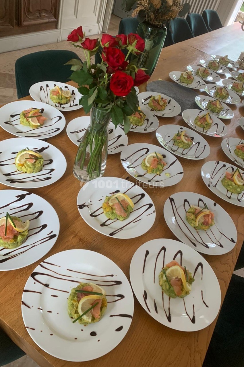 Assiettes dressées avec des entrées à base de saumon, avocat et citron, disposées sur une grande table en bois.