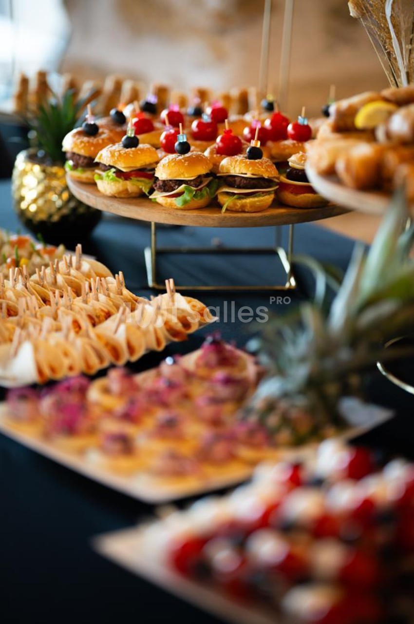 Plateau de mini-burgers, wraps et amuse-bouches variés disposés sur une table pour un buffet.
