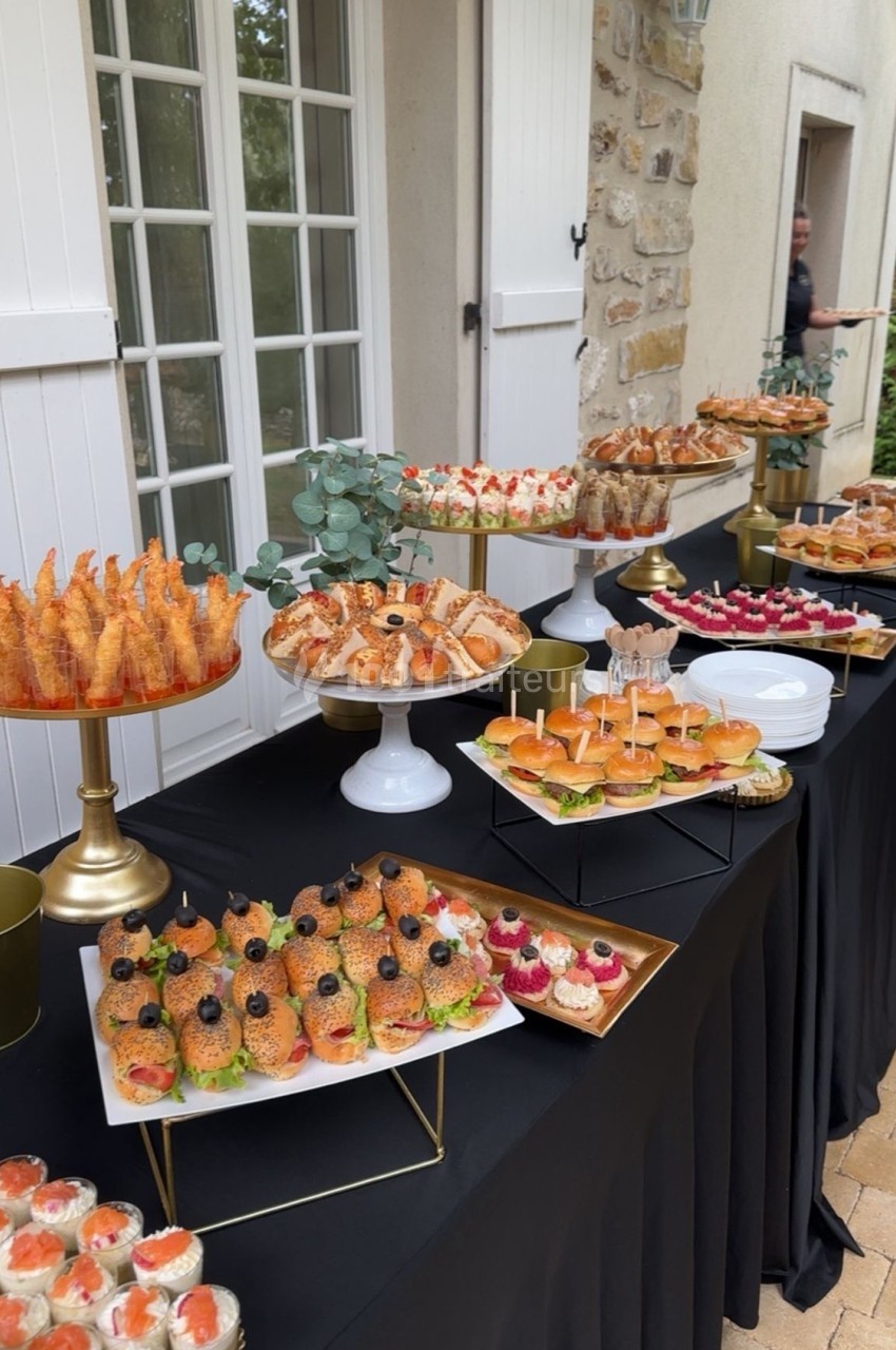 Buffet extérieur avec une variété de bouchées salées et sucrées disposées sur une table noire.