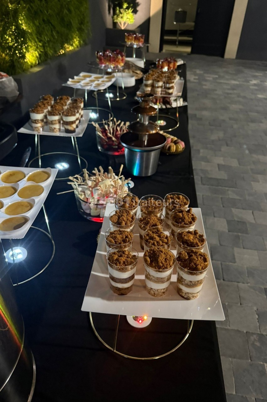 Buffet de desserts variés présenté sur une table noire, comprenant verrines, sucettes et autres douceurs.
