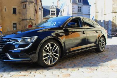 Voiture noire garée sur une place pavée, entourée de bâtiments historiques en arrière-plan.