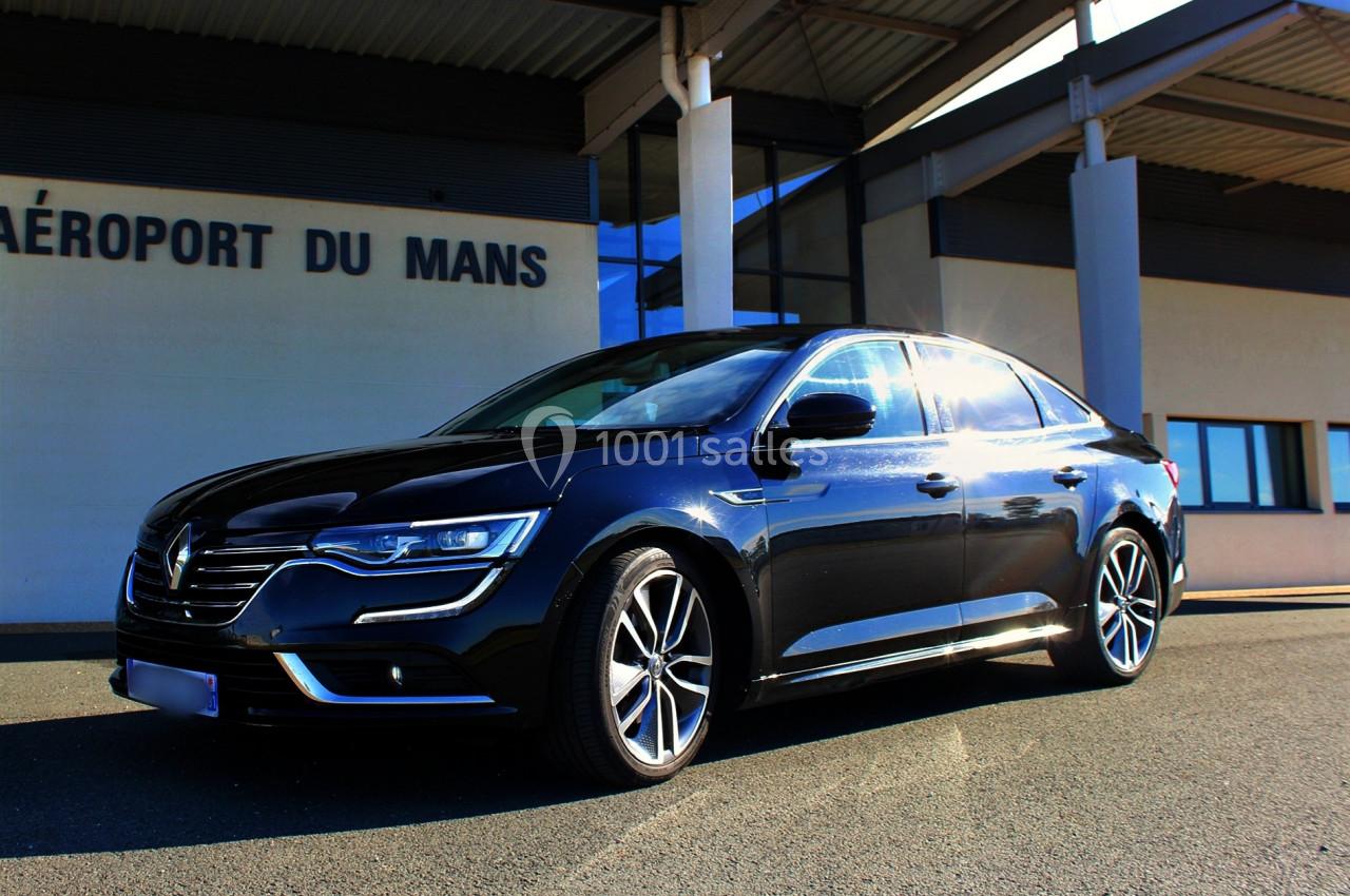 Voiture noire stationnée devant un bâtiment portant l'inscription ’Aéroport du Mans’.