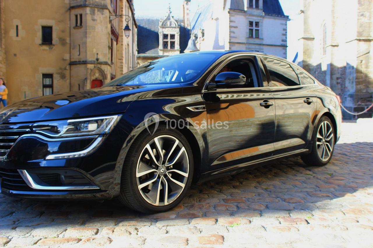 Voiture noire garée sur des pavés devant des bâtiments historiques en arrière-plan.