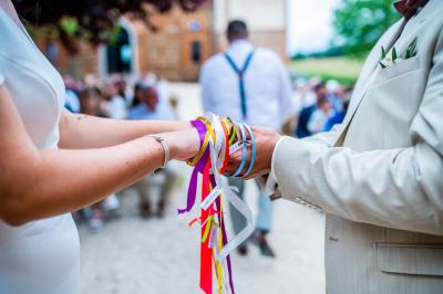 Salle de réception avec tables rondes dressées, décorées de fleurs, bougies et couverts élégants.