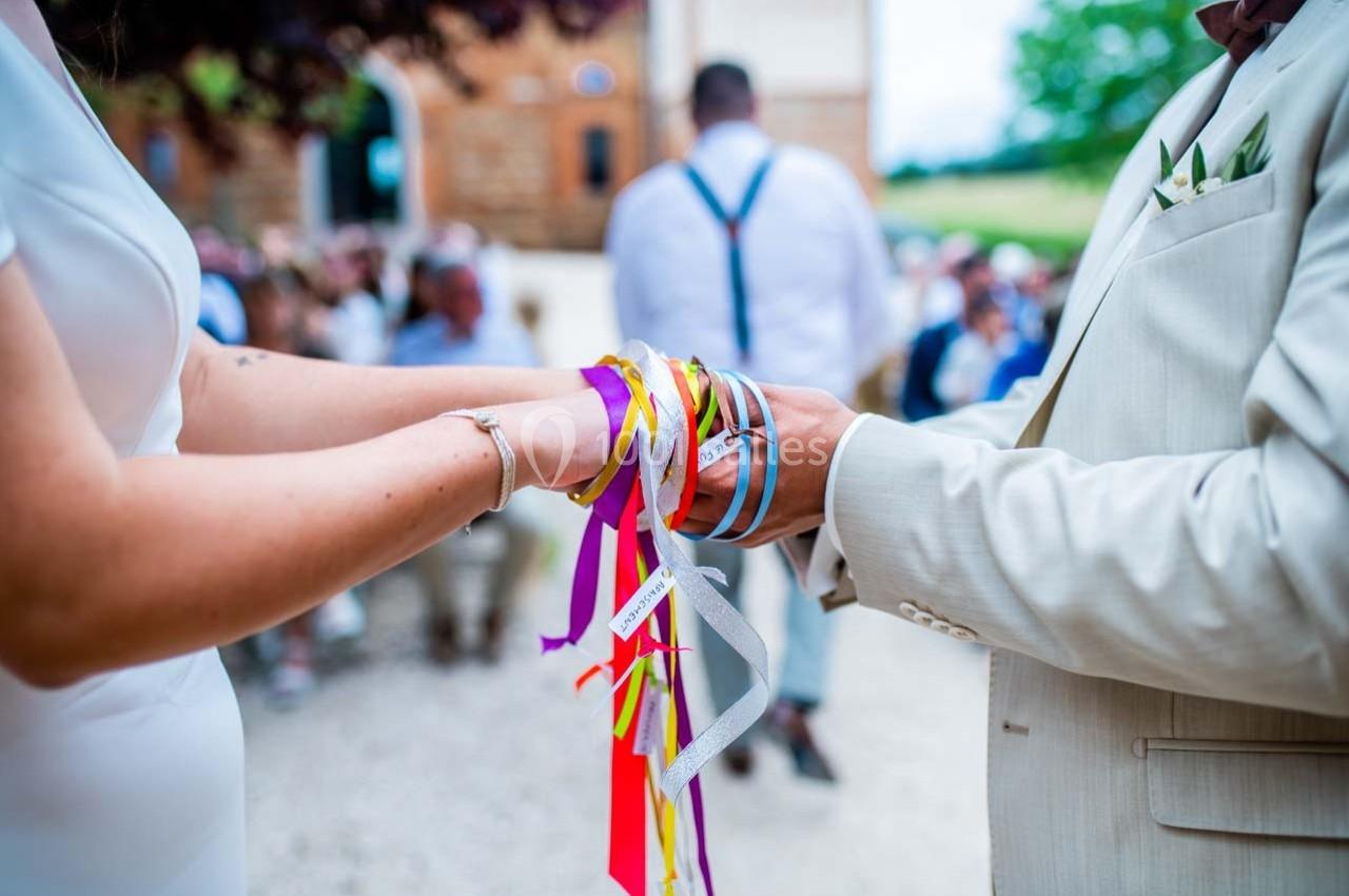 Deux personnes tiennent des rubans colorés lors d'une cérémonie en extérieur.