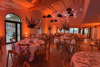 Salle de réception avec tables rondes dressées, décorées de fleurs, bougies et couverts élégants.