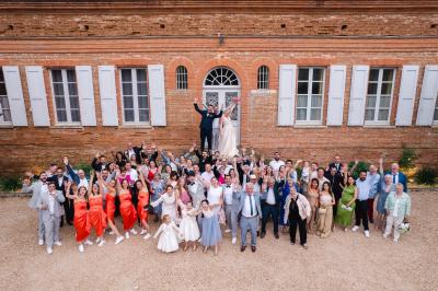 Salle de réception avec tables rondes dressées, décorées de fleurs, bougies et couverts élégants.