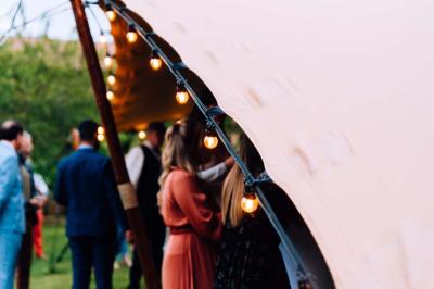 Salle de réception avec tables rondes dressées, décorées de fleurs, bougies et couverts élégants.