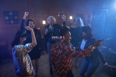 Un verre de champagne est rempli depuis une bouteille, entouré de trois autres verres sur une table en bois.