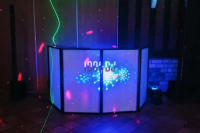 Un verre de champagne est rempli depuis une bouteille, entouré de trois autres verres sur une table en bois.