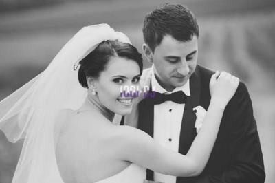 Un verre de champagne est rempli depuis une bouteille, entouré de trois autres verres sur une table en bois.