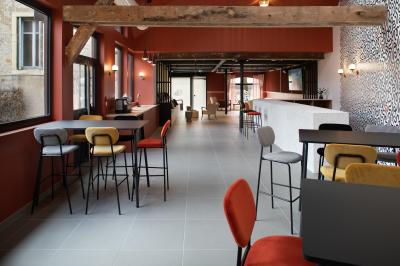 Espace salon avec canapés colorés, coussins variés, tables basses en bois et murs en pierre dans un cadre chaleureux.