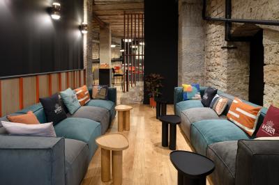 Espace salon avec canapés colorés, coussins variés, tables basses en bois et murs en pierre dans un cadre chaleureux.