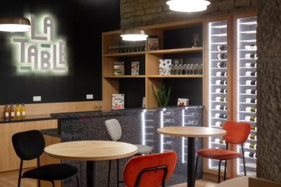 Espace salon avec canapés colorés, coussins variés, tables basses en bois et murs en pierre dans un cadre chaleureux.