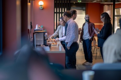 Deux femmes en tablier rouge discutent en préparant des ingrédients dans une cuisine moderne.