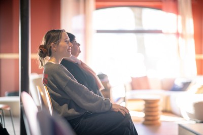 Deux femmes en tablier rouge discutent en préparant des ingrédients dans une cuisine moderne.
