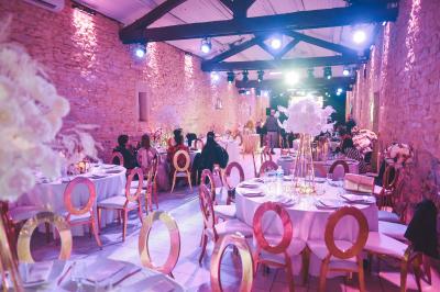 Décor de fête avec ballons beige et blanc, murs en pierre, présentoirs et un ours en peluche au centre.