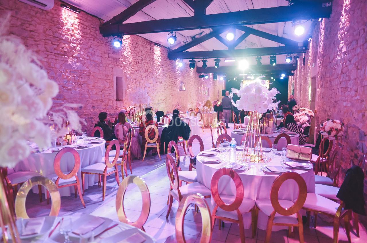 Salle de réception décorée avec des tables rondes, des chaises dorées et des arrangements floraux élégants.