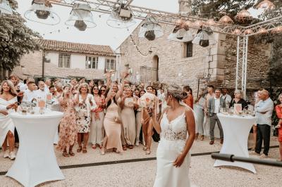 Décor de fête avec ballons beige et blanc, murs en pierre, présentoirs et un ours en peluche au centre.