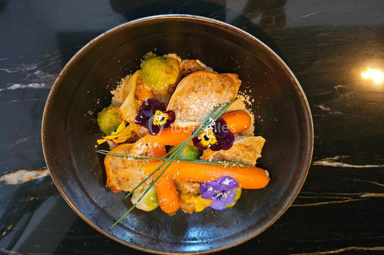 Assiette de légumes colorés avec carottes, choux de Bruxelles, fleurs comestibles et tranches de pain grillé.