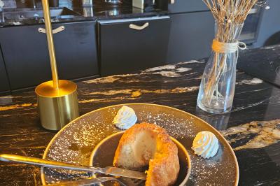 Salle de bain avec baignoire encastrée, douche à l'italienne, carrelage noir marbré et mosaïque dorée.