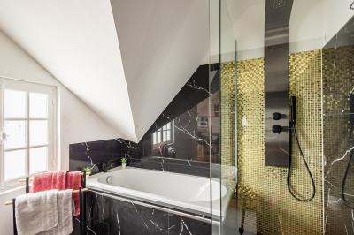 Douche moderne avec paroi en verre, entourée de carreaux dorés brillants formant un motif mosaïque.