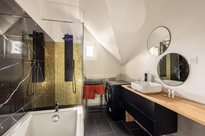 Douche moderne avec paroi en verre, entourée de carreaux dorés brillants formant un motif mosaïque.