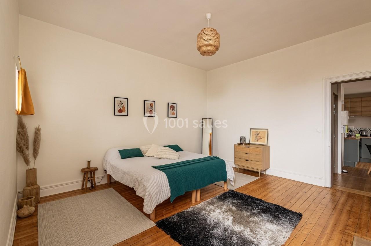 Chambre lumineuse avec lit double, parquet en bois, tapis, meubles en bois clair et décoration murale minimaliste.