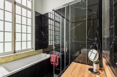 Douche moderne avec paroi en verre, entourée de carreaux dorés brillants formant un motif mosaïque.