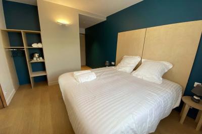 Un homme et une femme souriants derrière un comptoir en bois, avec des étagères de boissons en arrière-plan.