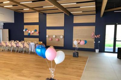 Un homme et une femme souriants derrière un comptoir en bois, avec des étagères de boissons en arrière-plan.