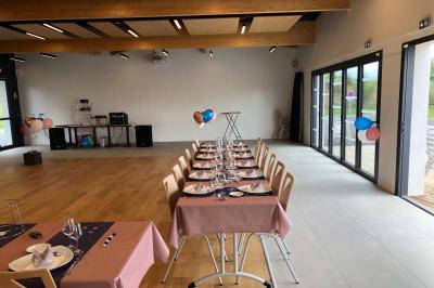 Un homme et une femme souriants derrière un comptoir en bois, avec des étagères de boissons en arrière-plan.