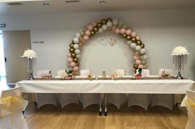 Un homme et une femme souriants derrière un comptoir en bois, avec des étagères de boissons en arrière-plan.