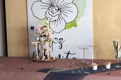 Un homme et une femme souriants derrière un comptoir en bois, avec des étagères de boissons en arrière-plan.