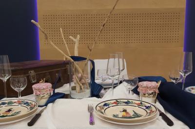 Un homme et une femme souriants derrière un comptoir en bois, avec des étagères de boissons en arrière-plan.