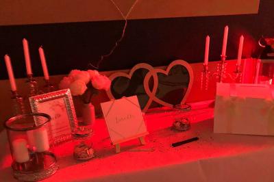 Un homme et une femme souriants derrière un comptoir en bois, avec des étagères de boissons en arrière-plan.