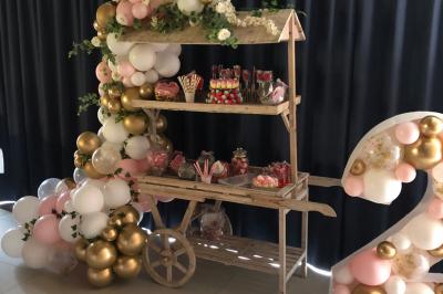 Un homme et une femme souriants derrière un comptoir en bois, avec des étagères de boissons en arrière-plan.