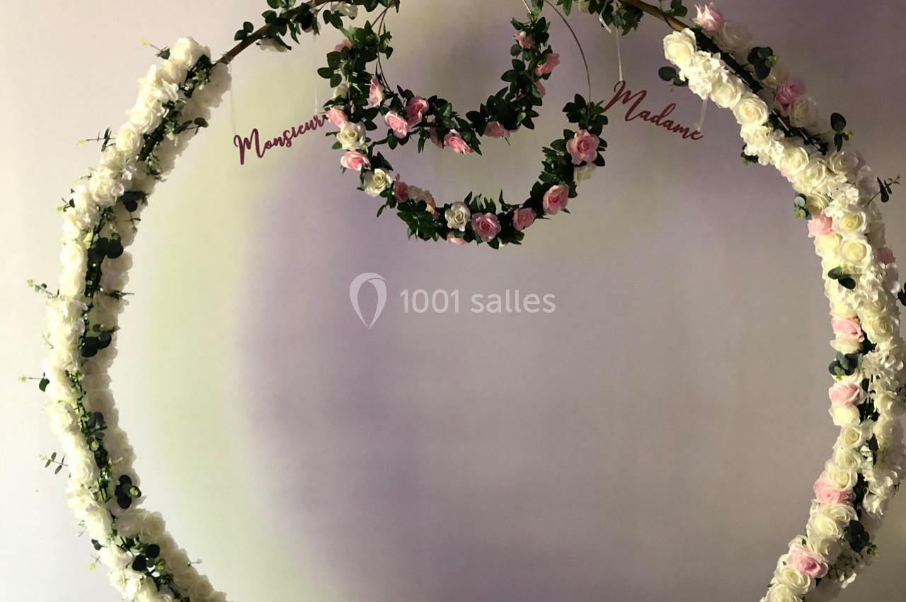 Cercle floral décoratif orné de fleurs blanches et roses, avec les inscriptions ’Monsieur’ et ’Madame’.