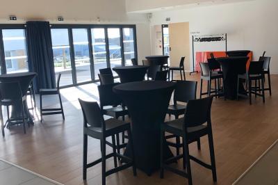 Kitchenette équipée avec évier, plaques de cuisson, bouilloire et vue sur une chambre avec lit double et parquet.