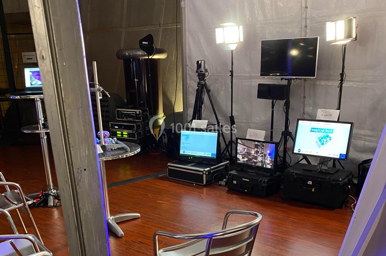 Installation technique avec écrans, projecteurs et équipements audiovisuels dans une salle aux murs clairs.