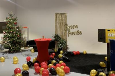 Salle lumineuse avec rangées de chaises, tables hautes et buffet en arrière-plan, sous un plafond industriel.