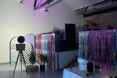 Salle lumineuse avec rangées de chaises, tables hautes et buffet en arrière-plan, sous un plafond industriel.