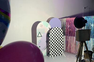 Salle lumineuse avec rangées de chaises, tables hautes et buffet en arrière-plan, sous un plafond industriel.