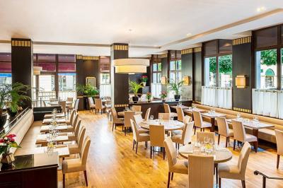 Salle de petit-déjeuner avec buffet varié, tables dressées, éclairage chaleureux et décor moderne en bois sombre.